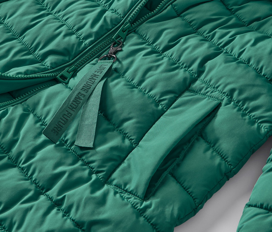 Detail zelenej prešívanej bundy s kapucňou.