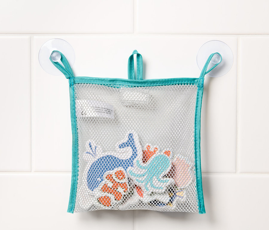 Sieťka na hračky do vane s desiatimi hračkami do vody Meerestiere visí na bielych dlaždiciach.