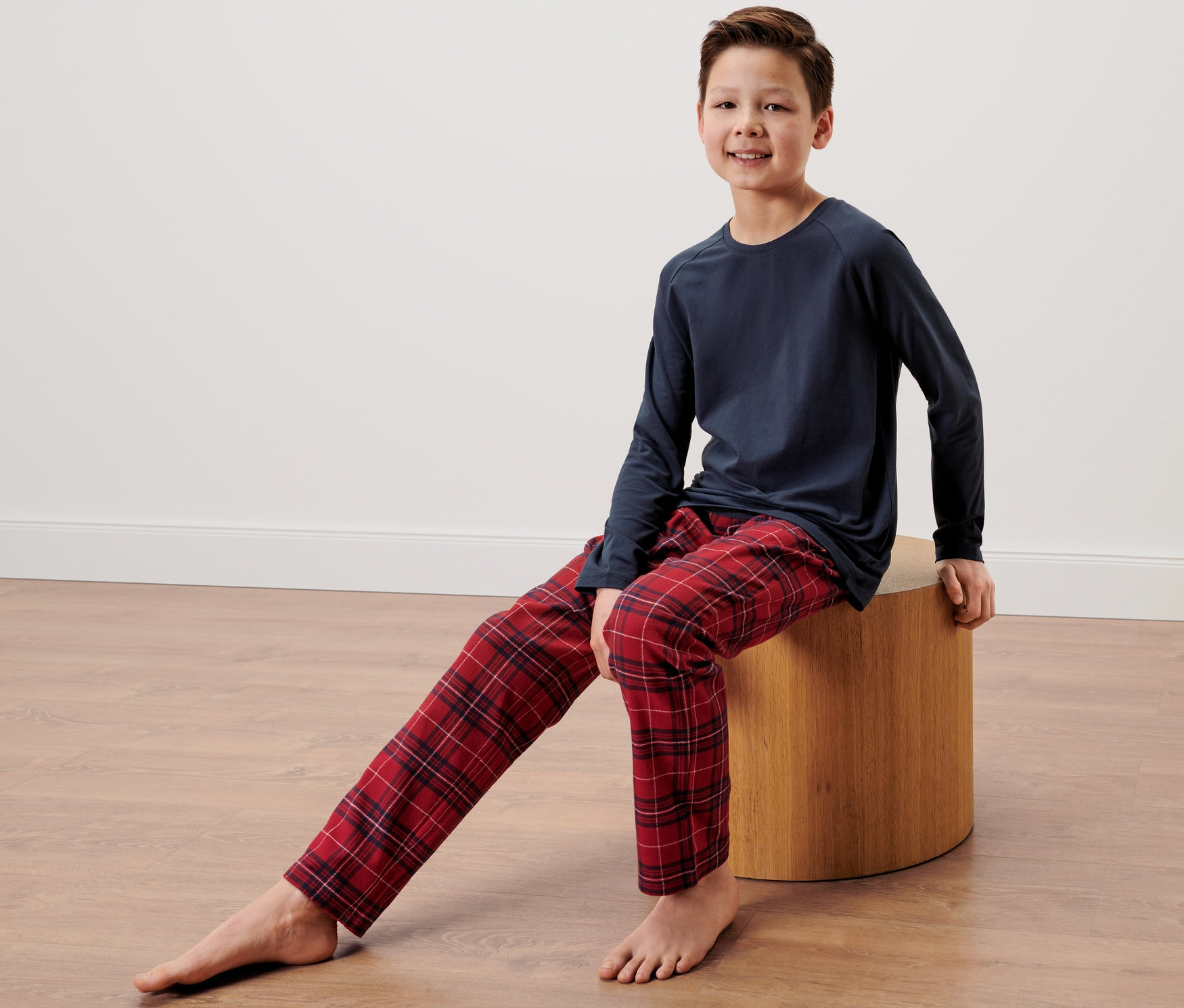 Chlapec sedí na stoličke a má na sebe detské flanelové pyžamo.