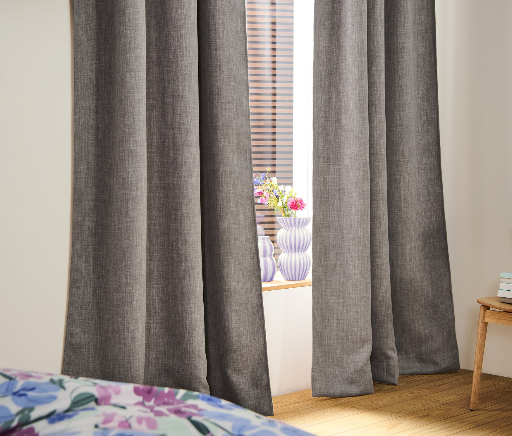 Dva zatemňujúce závesy pri okne. V oknách sú žalúzie.