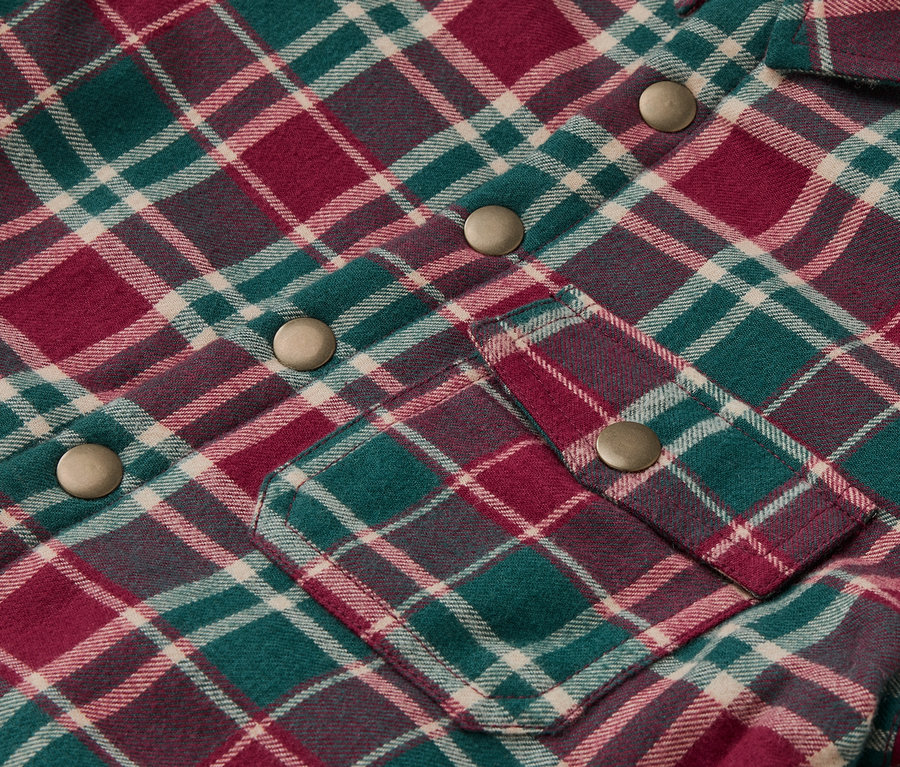 Detail detskej flanelovej bundy s károvaným vzorom a cvokmi.
