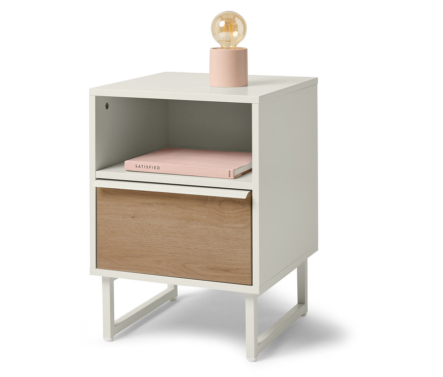 Biely nočný stolík s drevenou zásuvkou, knihou a lampou.
