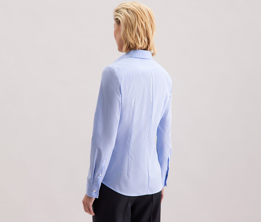 Pohľad zozadu na ženu s blond vlasmi po ramená v svetlomodrej blúzke Seidensticker Slim Fit non iron.
