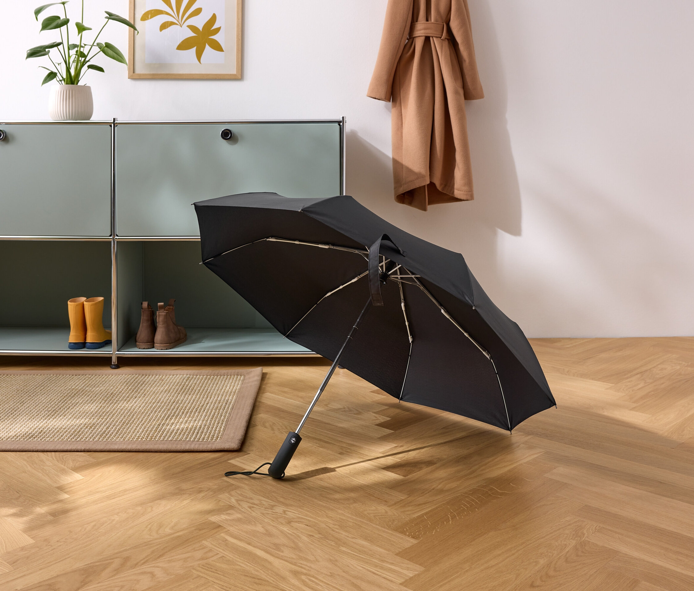 Čierny dáždnik leží na parketovej podlahe v chodbe.