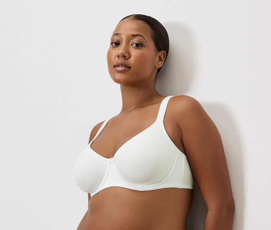 Portrét ženy s hnedou pleťou v bielej podprsenke.