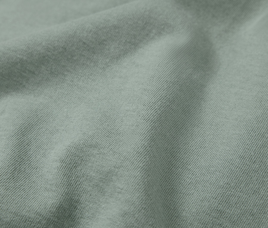 Detailný záber na svetlozelenú látku s diagonálnym rebrovaním.