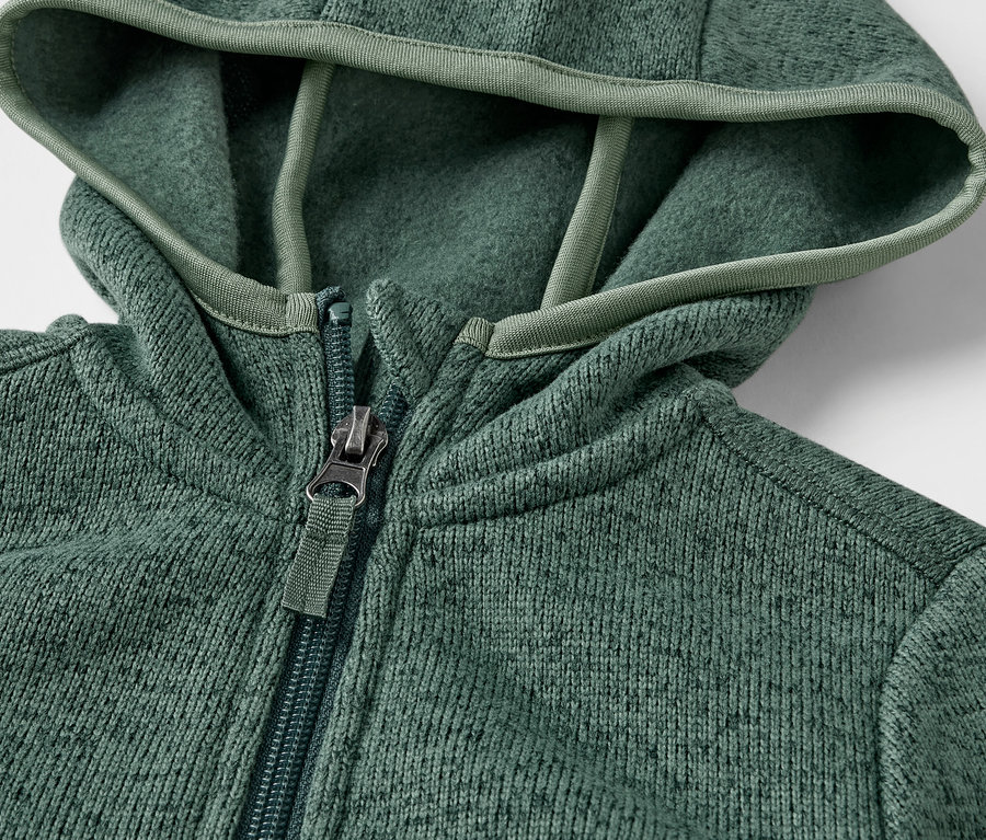 Detail detskej mikiny z pleteného fleecu so zipsom a kapucňou.