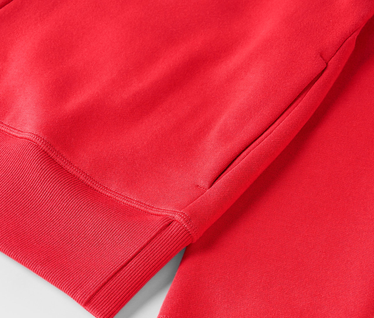 Detail červenej mikiny s kapucňou s rebrovaným lemom.