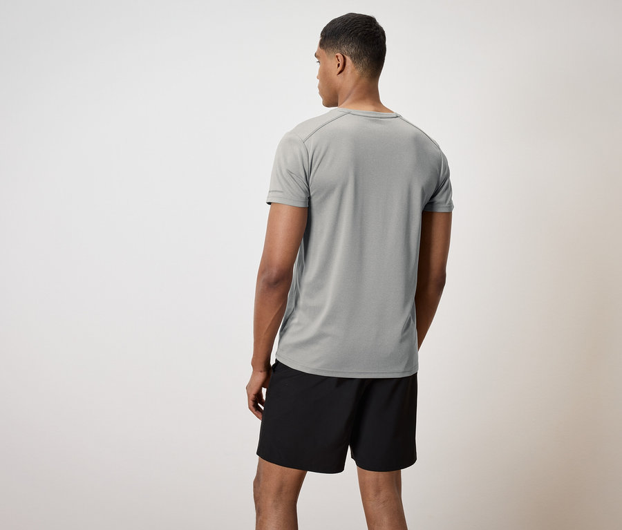 Muž chrbtom k fotoaparátu má na sebe sivé tričko a čierne šortky.