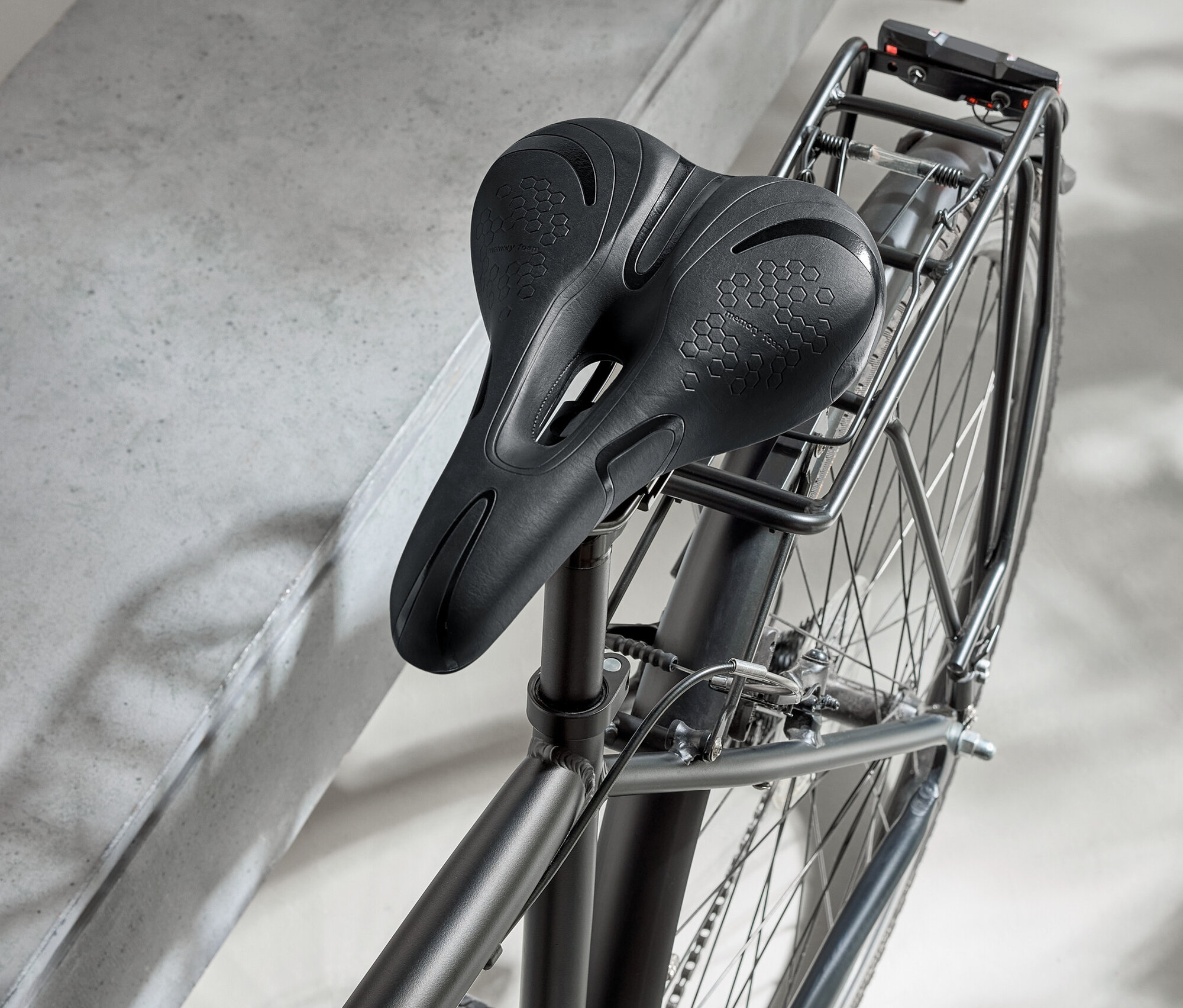 Čierny bicykel s čiernym sedlom a čiernou prilbou na betónovom povrchu.