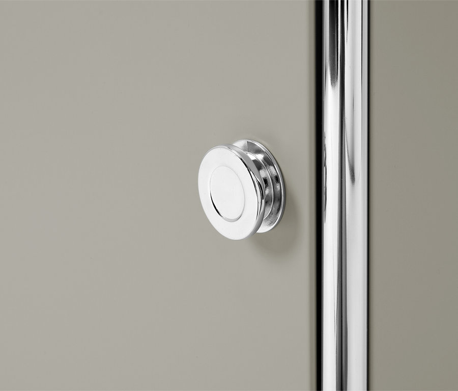 Detailný záber na sivé dvierka skrinky s okrúhlou striebornou rukoväťou a striebornou tyčou.