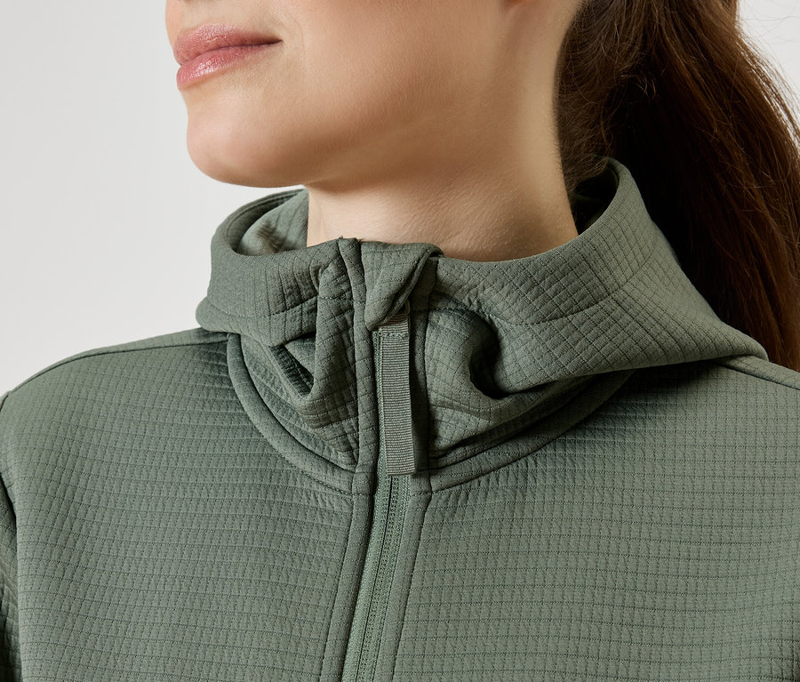 Detailný záber ženy v zelenej mikine s kapucňou na zips.