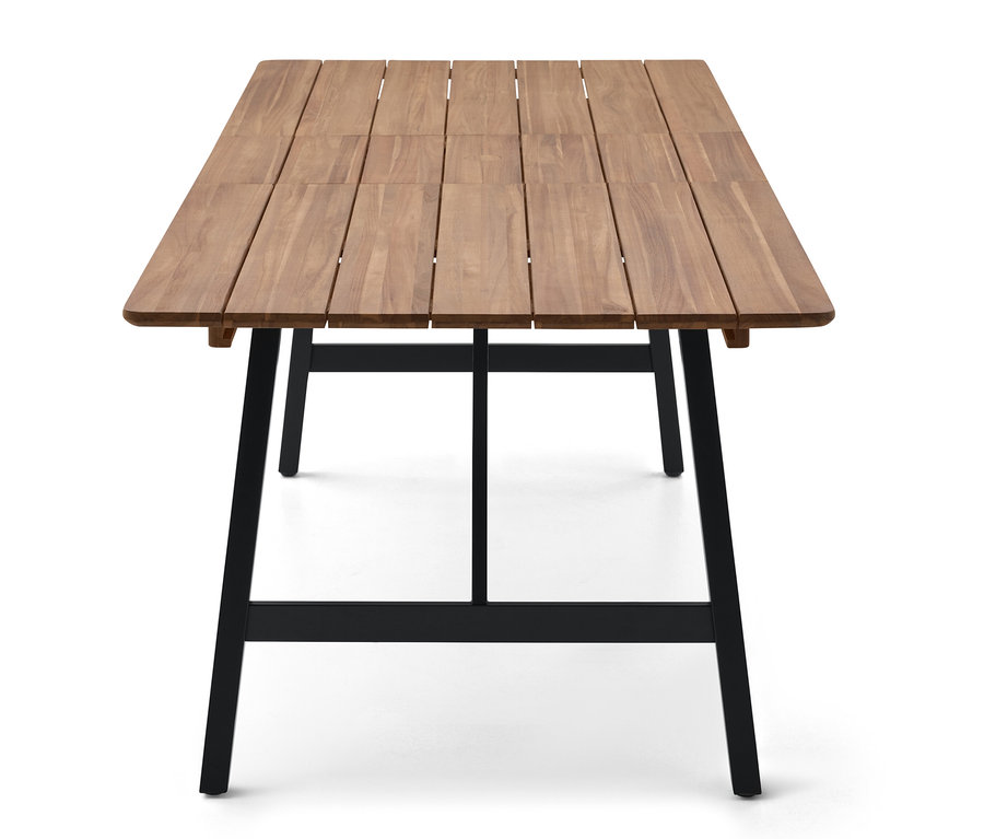Detailný záber na obdĺžnikový drevený stôl s čiernymi kovovými nohami na bielom pozadí.