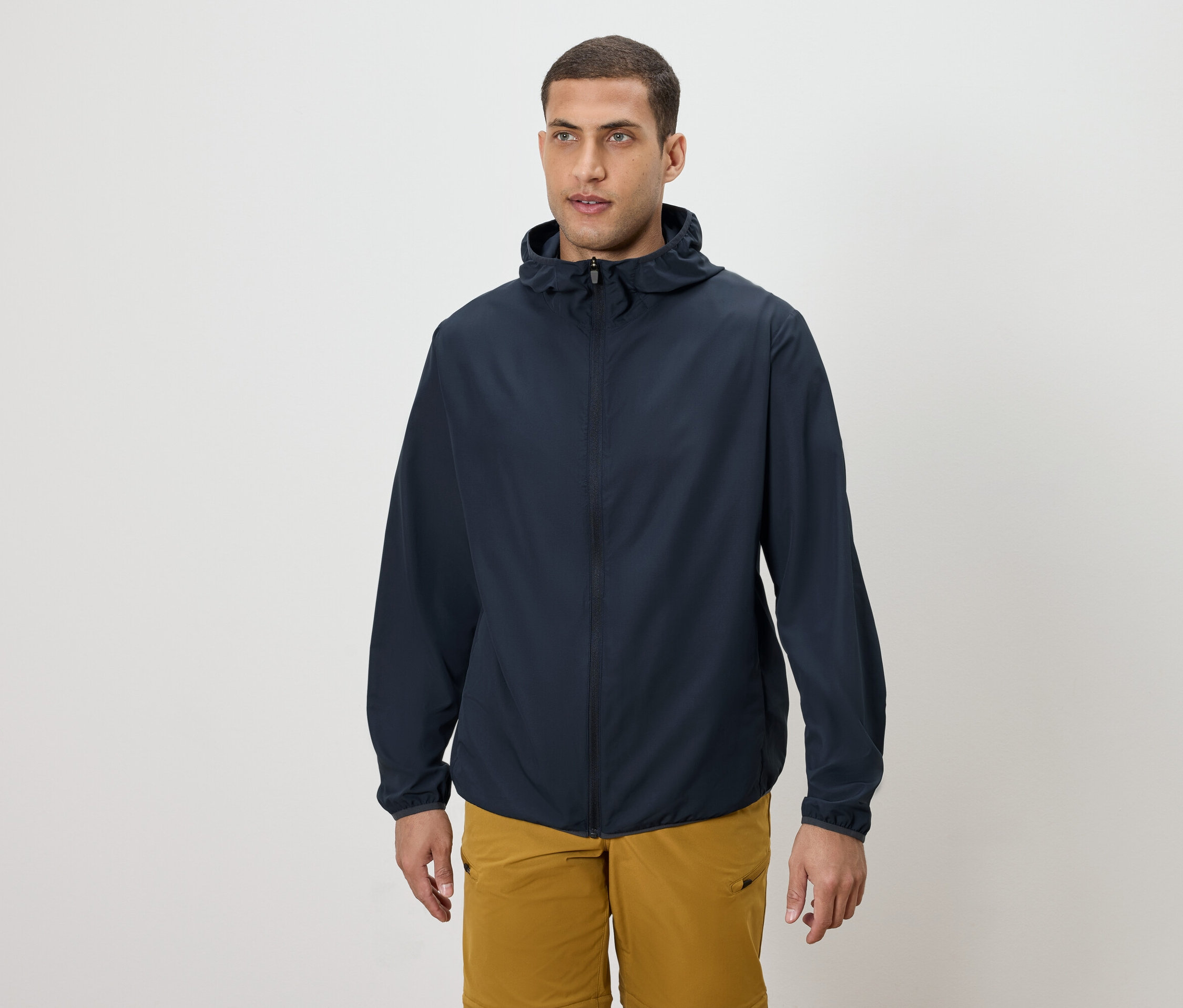 Muž má na sebe tmavomodrú bundu s kapucňou a zlaté šortky.