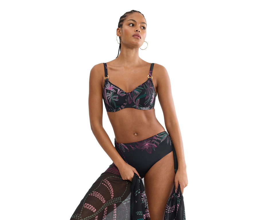 Žena má na sebe čierne bikiny s kvetinovým vzorom a drží zodpovedajúce pareo.