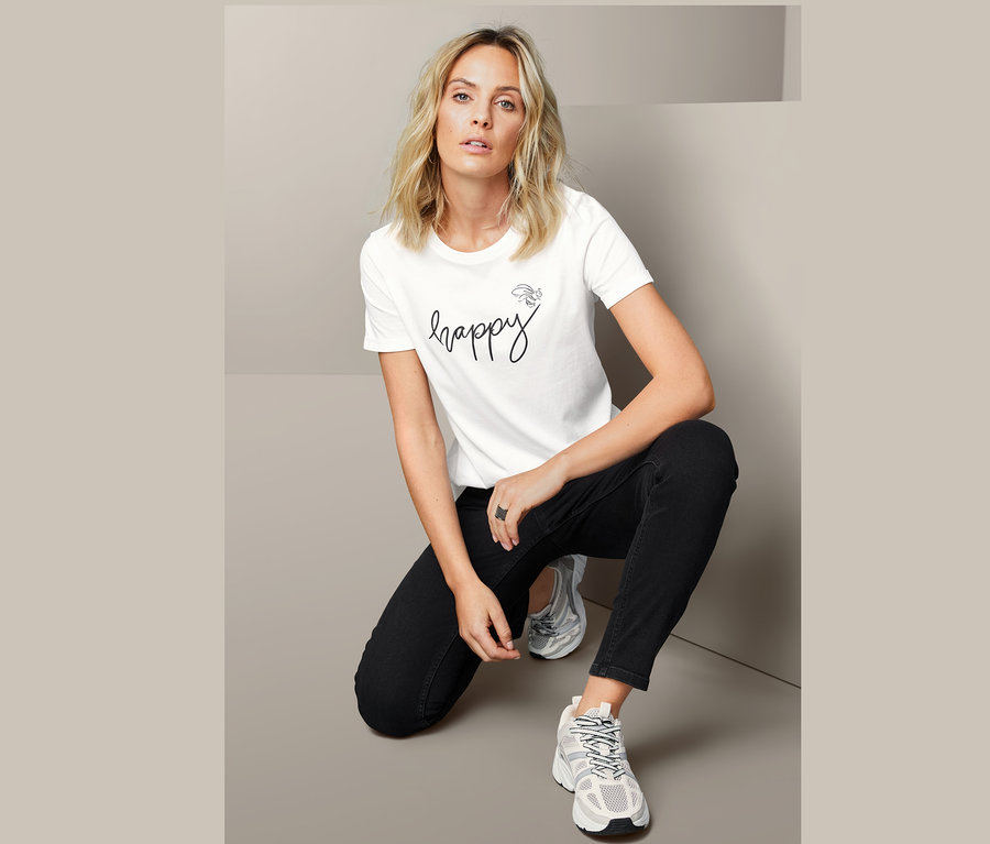 Žena kľačí a má na sebe statement tričko.