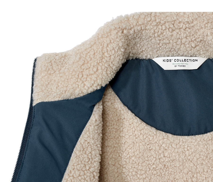 Detail detskej prešívanej vesty s hebkým plyšom, vnútorná strana je modrá.