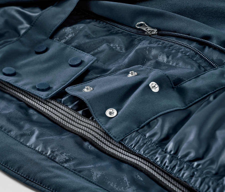 Detail námorníckej modrej lyžiarskej bundy so zipsom a gombíkmi.