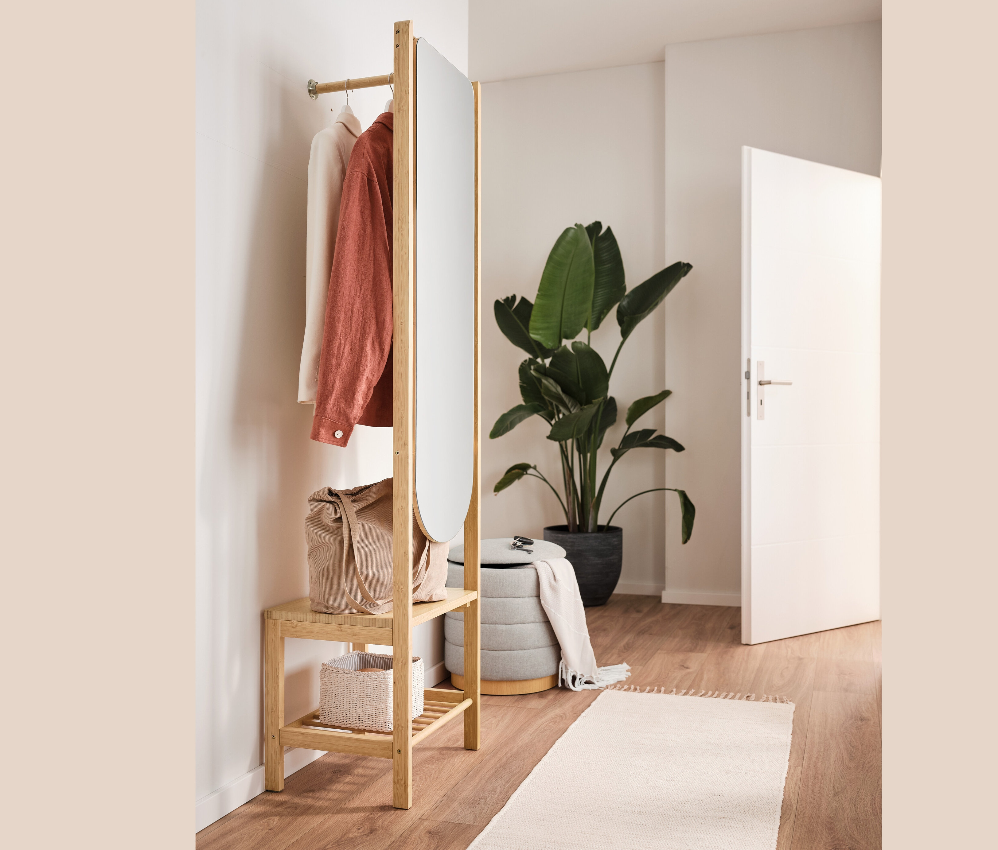 Vešiaková skriňa so zrkadlom a odkladacou plochou, taburetka s úložným priestorom, taška a oblečenie v interiéri.