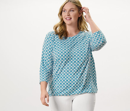 Žena stojí a pózuje v blúzkovom tričku s celoplošnou potlačou a sedemosminových elastických nohaviciach, biele.