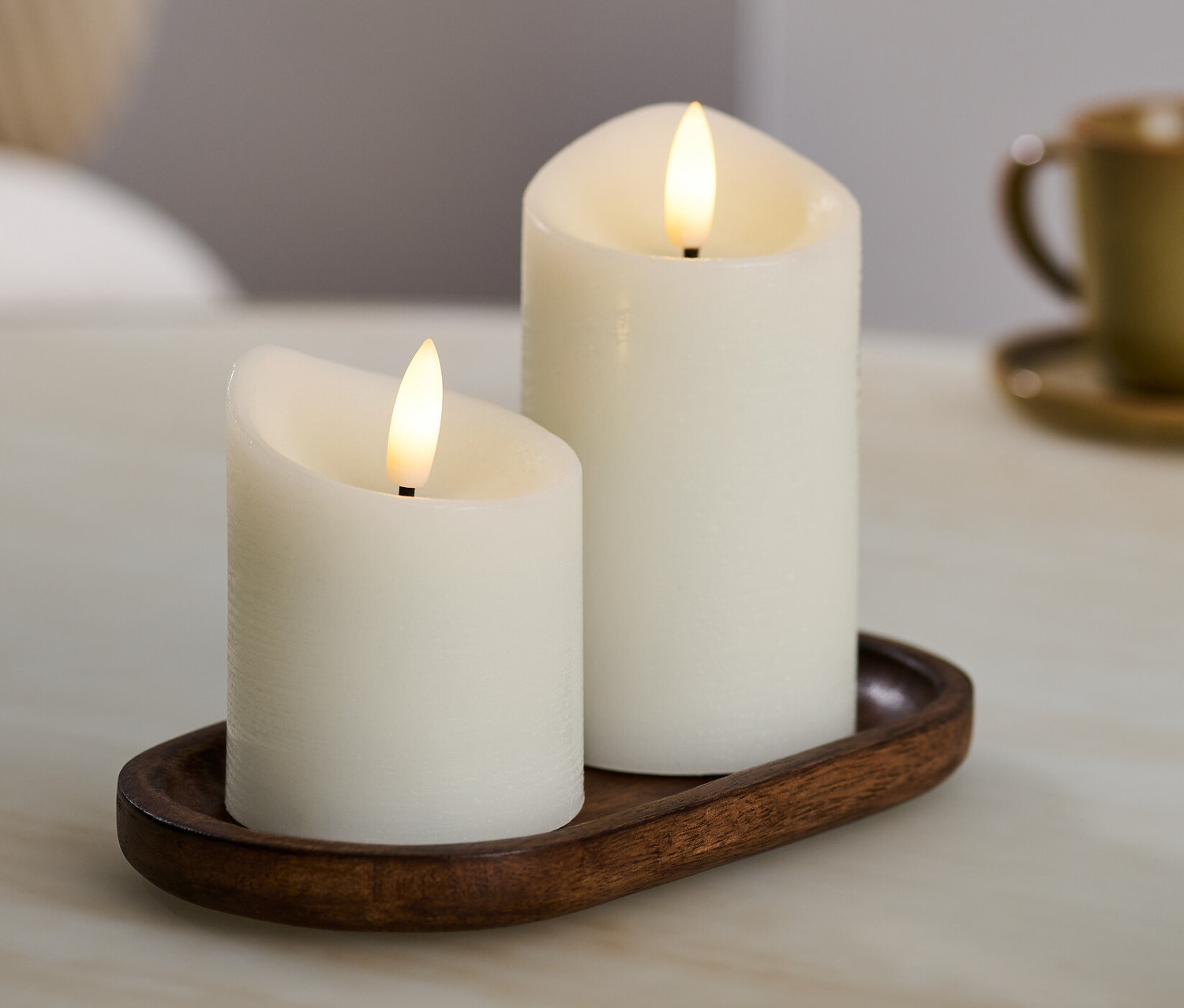 Dve krémové LED sviečky z pravého vosku na hnedom podnose.
