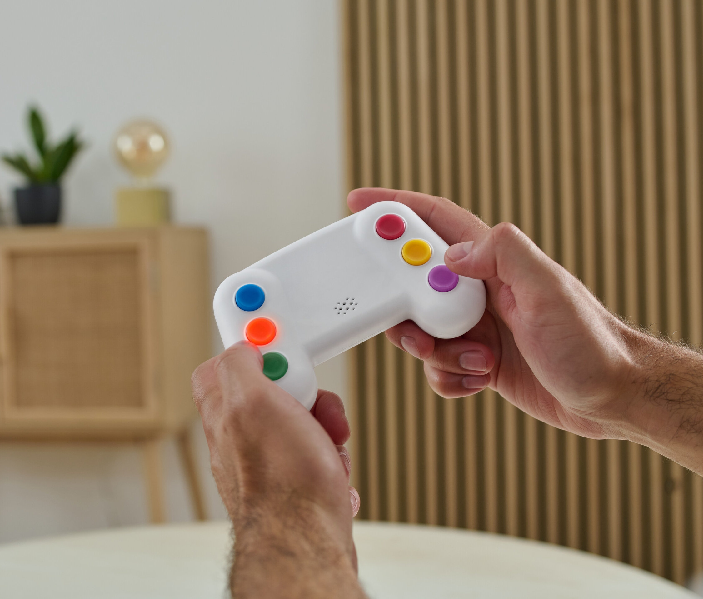 Muž drží v rukách elektronický precvičovateľ pamäti s farebnými tlačidlami.