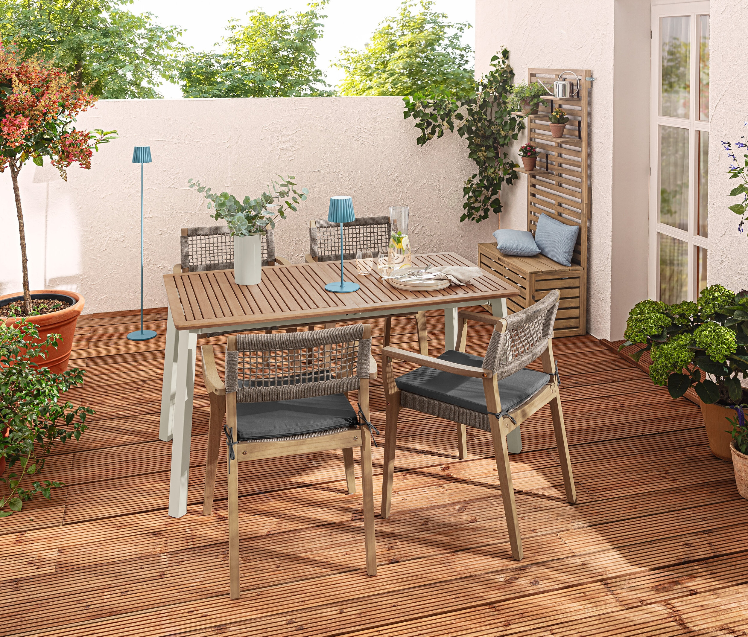 Vonkajšia terasa s vysúvacím stolom »Liska«, stohovateľnými stoličkami, modrou LED stolovou a stojacou lampou a vankúšmi.