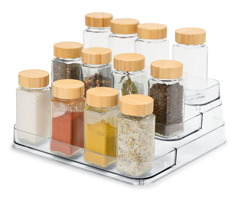 Na priehľadnom trojvrstvovom organizéri je 12 sklenených koreničiek s drevenými viečkami.