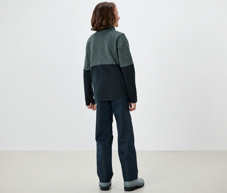 Chlapec stojí chrbtom a má na sebe hybridnú pletenú fleecovú bundu.