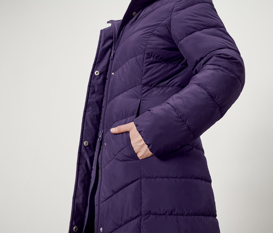 Detail fialovej prešívanej bundy s rukou vo vrecku.