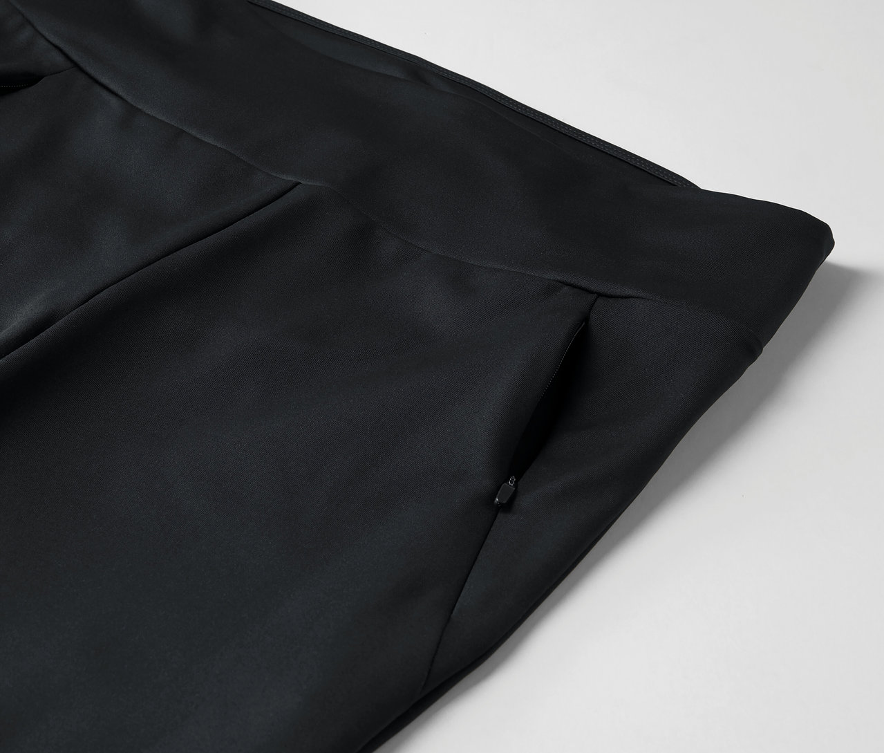 Detail čiernych nohavíc s vreckom na zips.