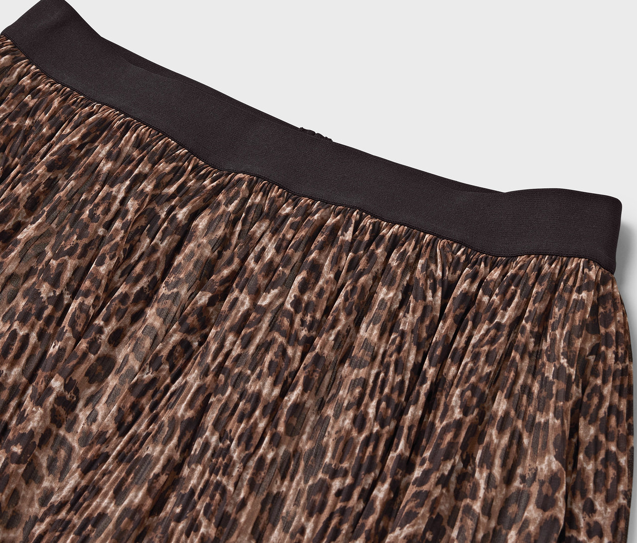 Detail hnedej sukne so zvieracím vzorom a čiernym pásom.