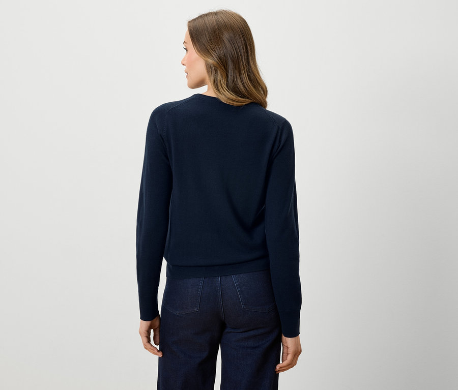 Zozadu je vidieť žena v tmavomodrom svetri a tmavých džínsoch.