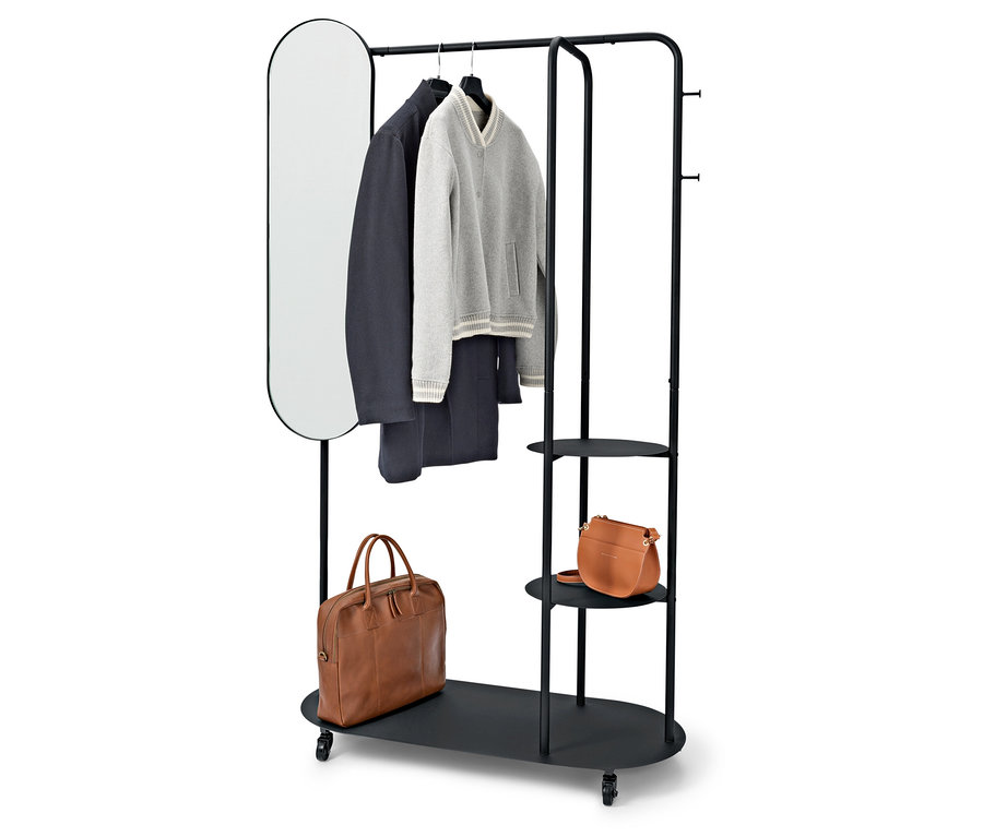 Čierny stojan na oblečenie s oválnym zrkadlom, kabátom, svetrom, nohavicami a dvoma hnedými taškami.