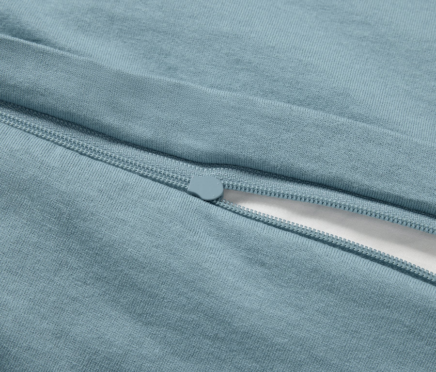 Detail svetlomodrej obliečky na prikrývku so zipsom a kúskom bielej látky.