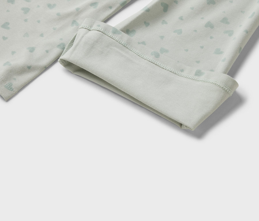 Detail svetlozelených legín s potlačou svetlomodrých srdiečok a ohrnutým lemom.