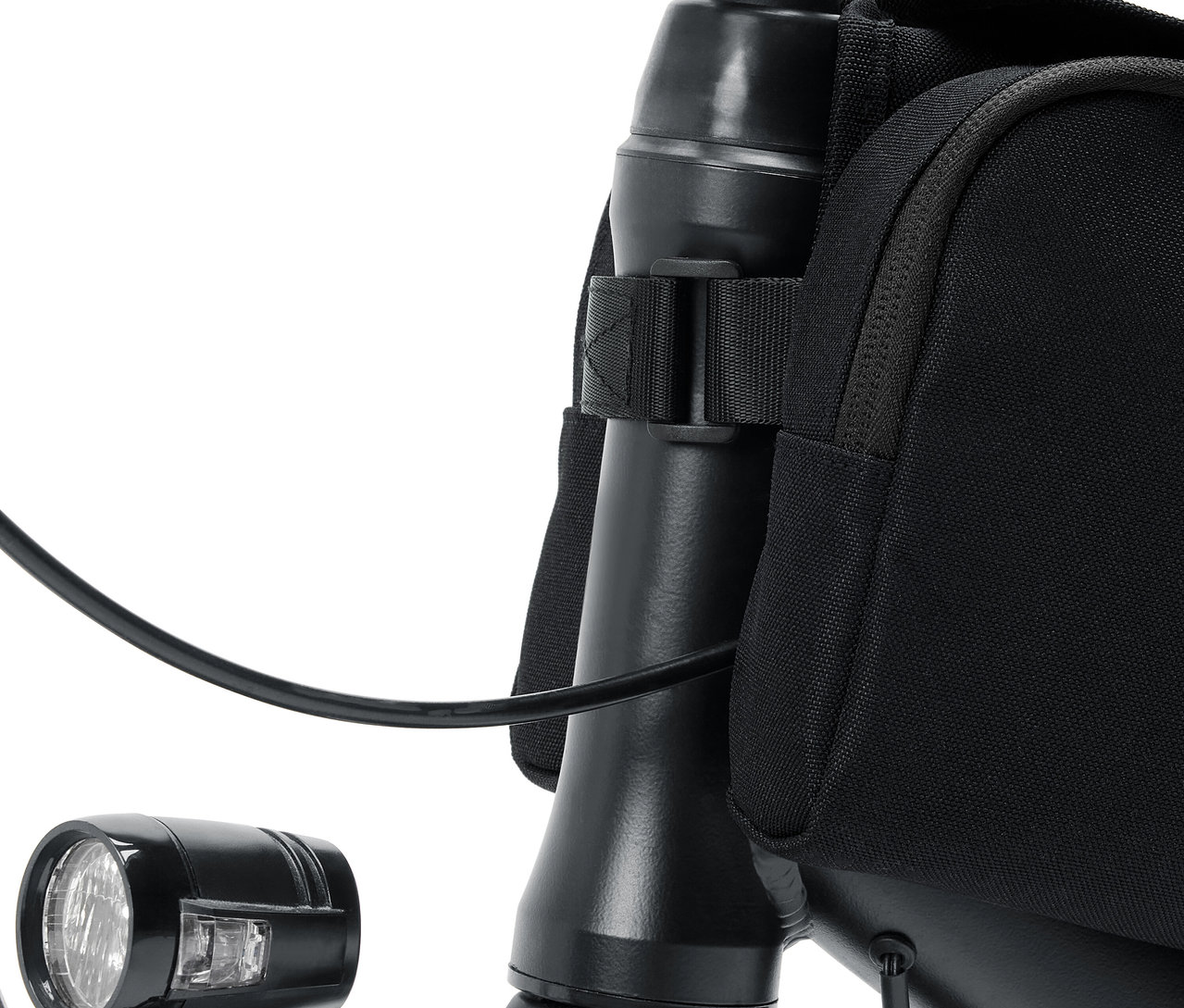 Detail riadidiel bicykla s lampou a čiernou taškou.