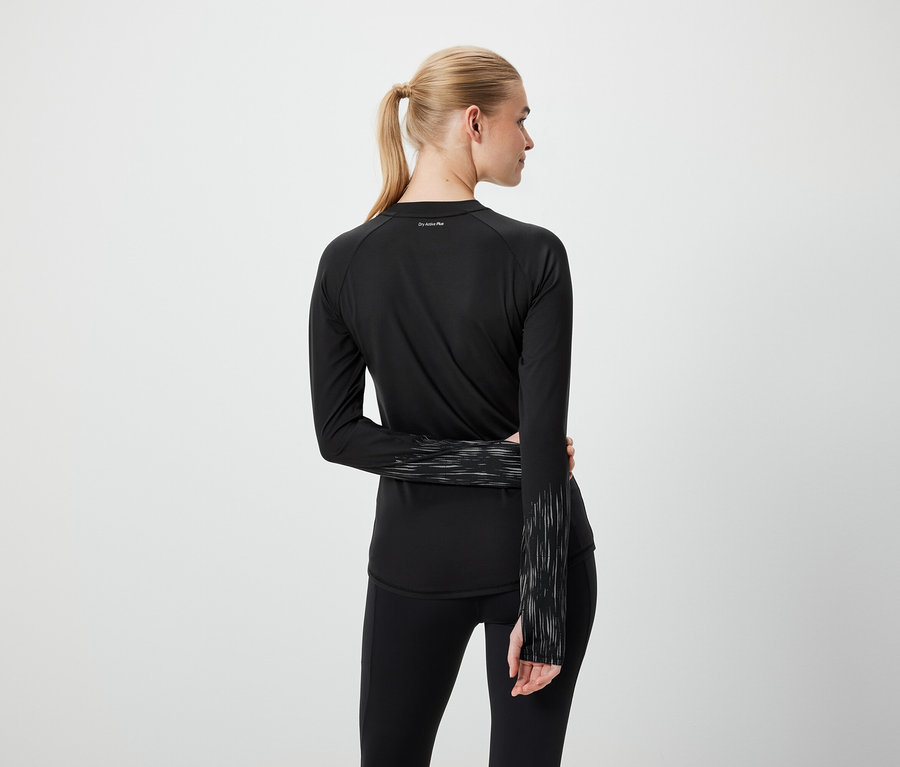 Blondína s copom v čiernom športovom oblečení zozadu.