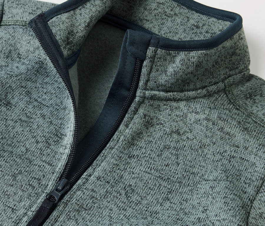 Detail detskej hybridnej bundy z pleteného flísu s rozopnutým zipsom.