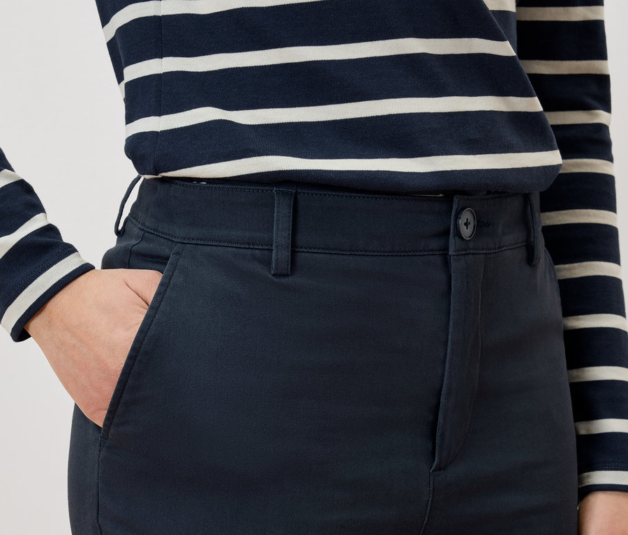 Detail osoby s rukou vo vrecku nohavíc a v pruhovanom tričku.