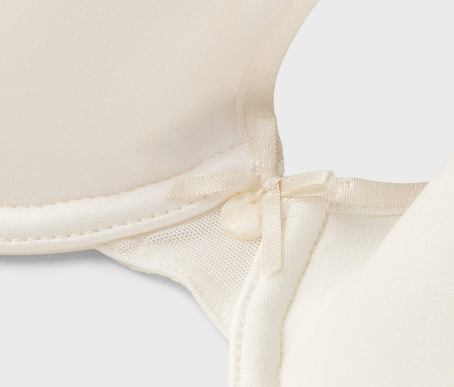 Detailný pohľad na krémovú podprsenku s mašličkou.