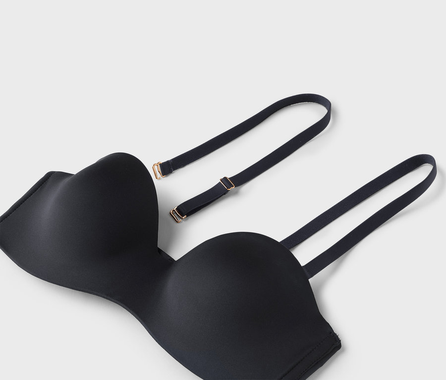 Detailný záber na čiernu podprsenku bez ramienok s odnímateľnými ramienkami na bielom pozadí.