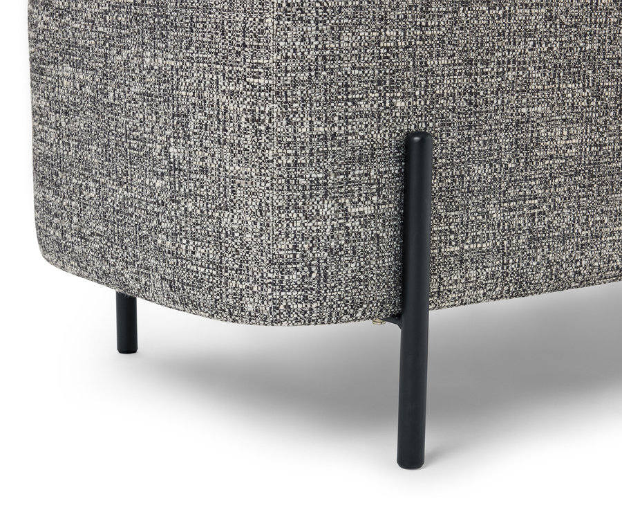 Detail rohu kresla so sivou melírovanou látkou a čiernymi nohami na bielom pozadí.