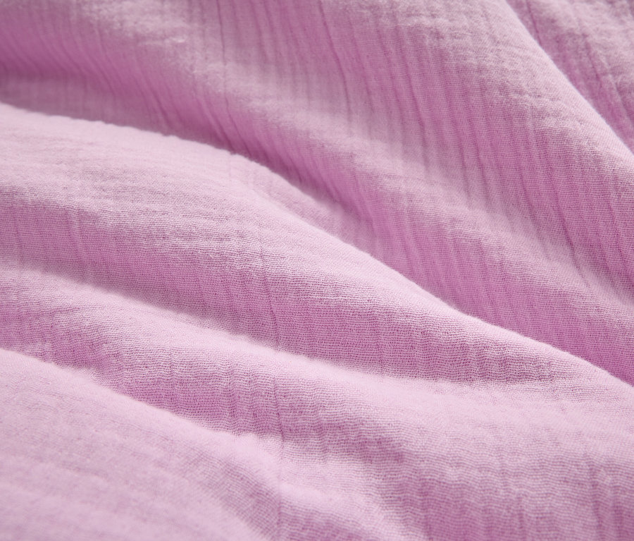 Detailná fotografia pokrčenej, svetlofialovej látky.