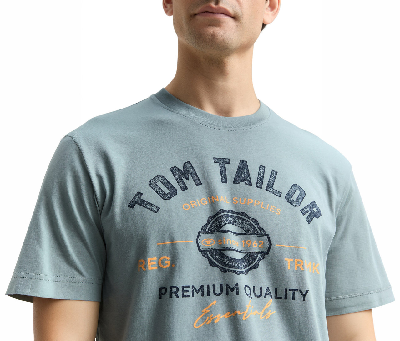 Muž má na sebe tričko Tom Tailor s logom, mätová sivá.