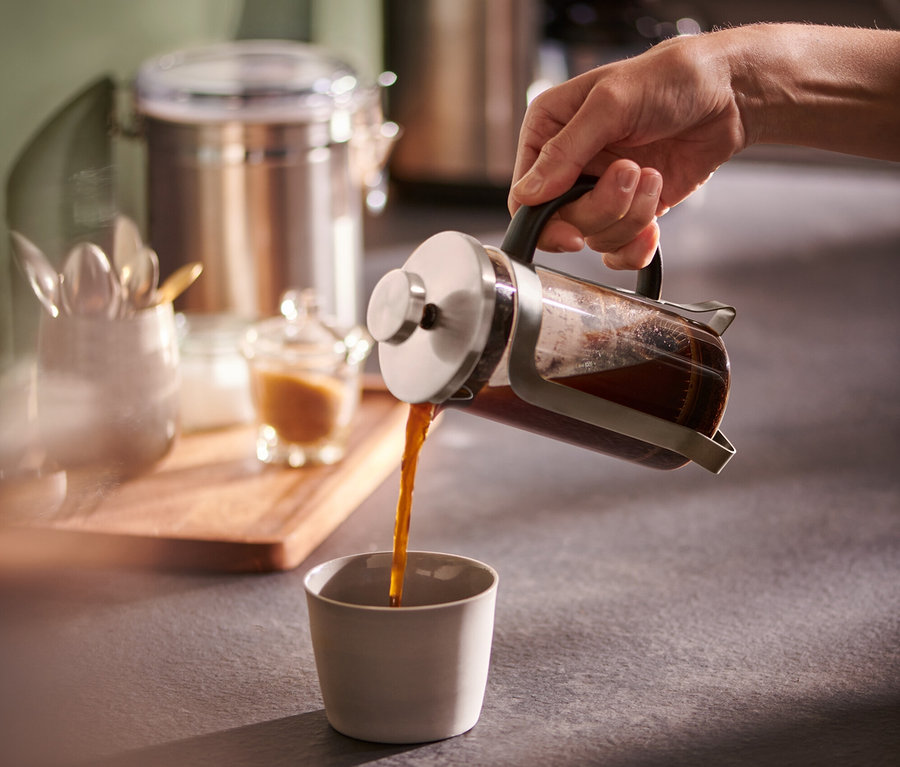 Ruka nalieva kávu z kanvice french press 300 ml striebornej farby do šálky.