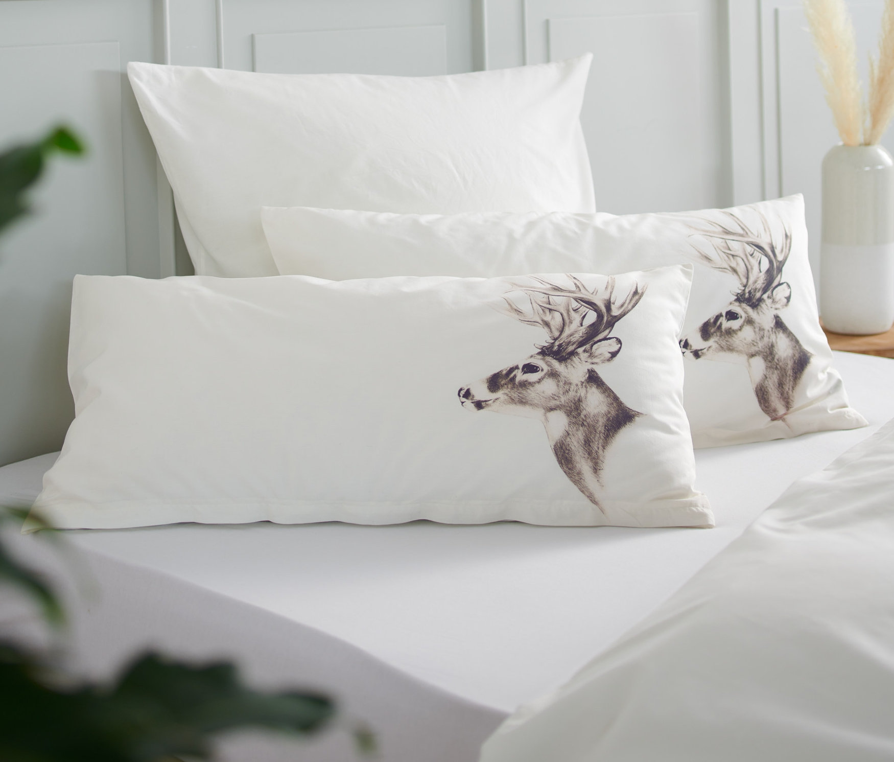 Na posteli ležia dve perkálové obliečky na vankúše, jedna s motívom jeleňa.