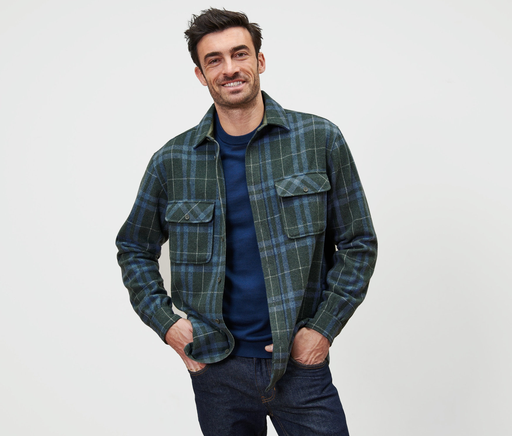 Muž pózuje v zelenej a modrej kockovanej flanelovej košeľovej bunde.