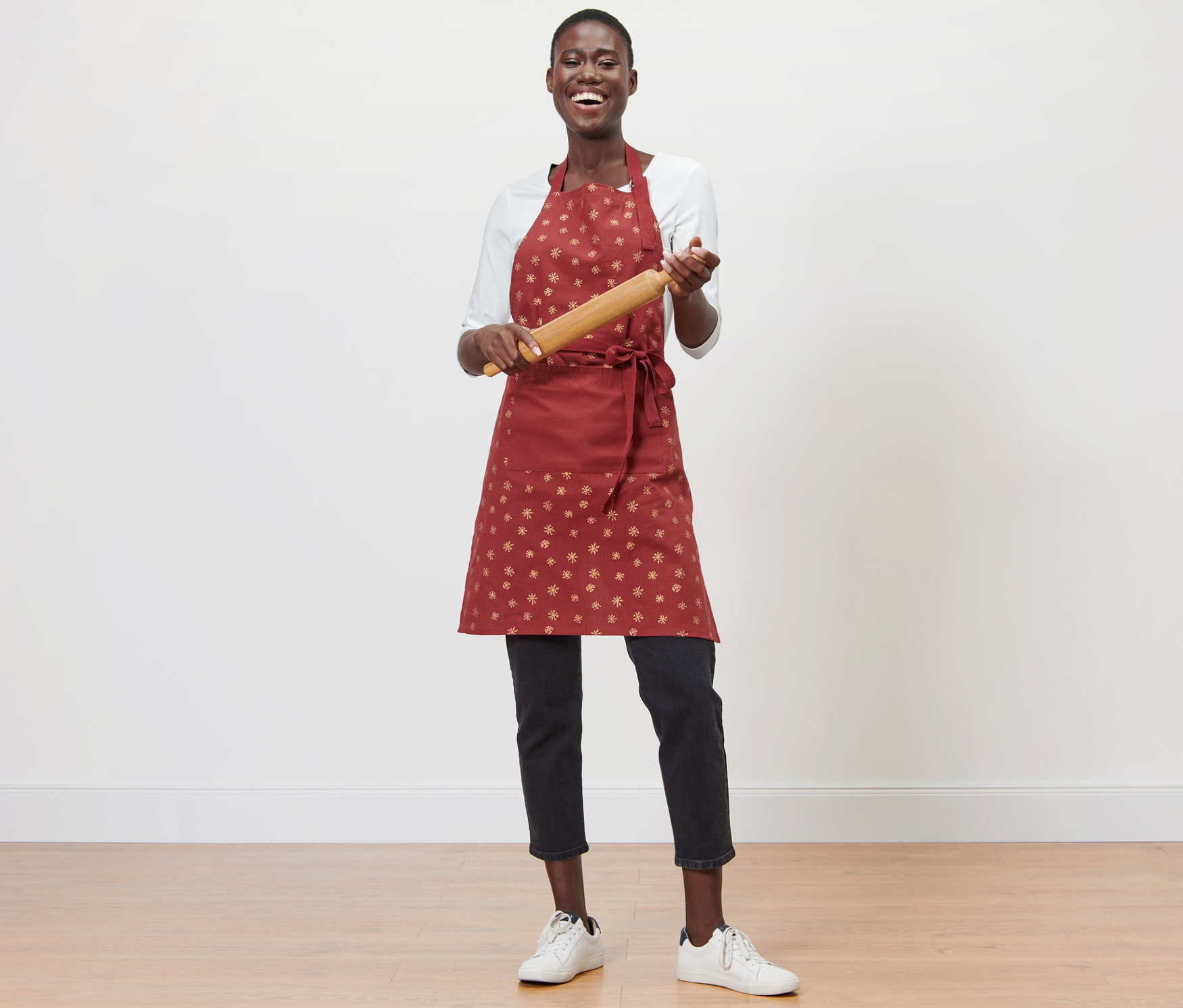 Žena drží valček na cesto a má na sebe kuchynskú zásteru.