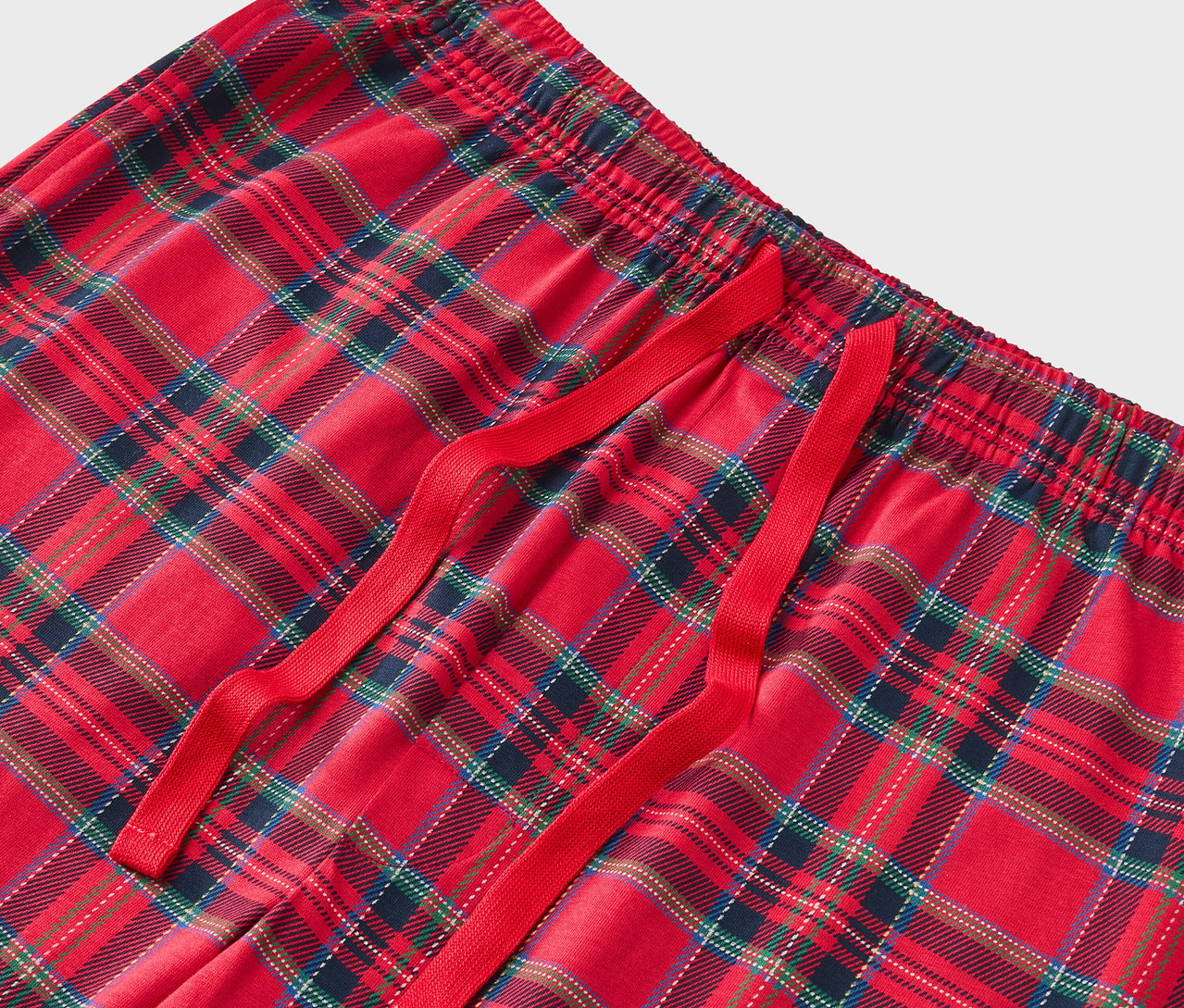 Detail červených károvaných pyžamových nohavíc s červenou sťahovacou šnúrkou.